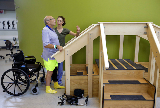 William Lytton, of Scarsdale, N.Y., left, is assisted by physical therapist Caitlin Geary, right, as he prepares to climb a set of stairs at Spaulding Rehabilitation Hospital in Boston on Tuesday while recovering from a shark attack. Lytton suffered deep puncture wounds to his leg and torso after being attacked by a shark on Aug. 15 while swimming off a beach, in Truro, Mass. Lytton injured a tendon in his arm while fighting off the shark. AP Photo/Steven Senne