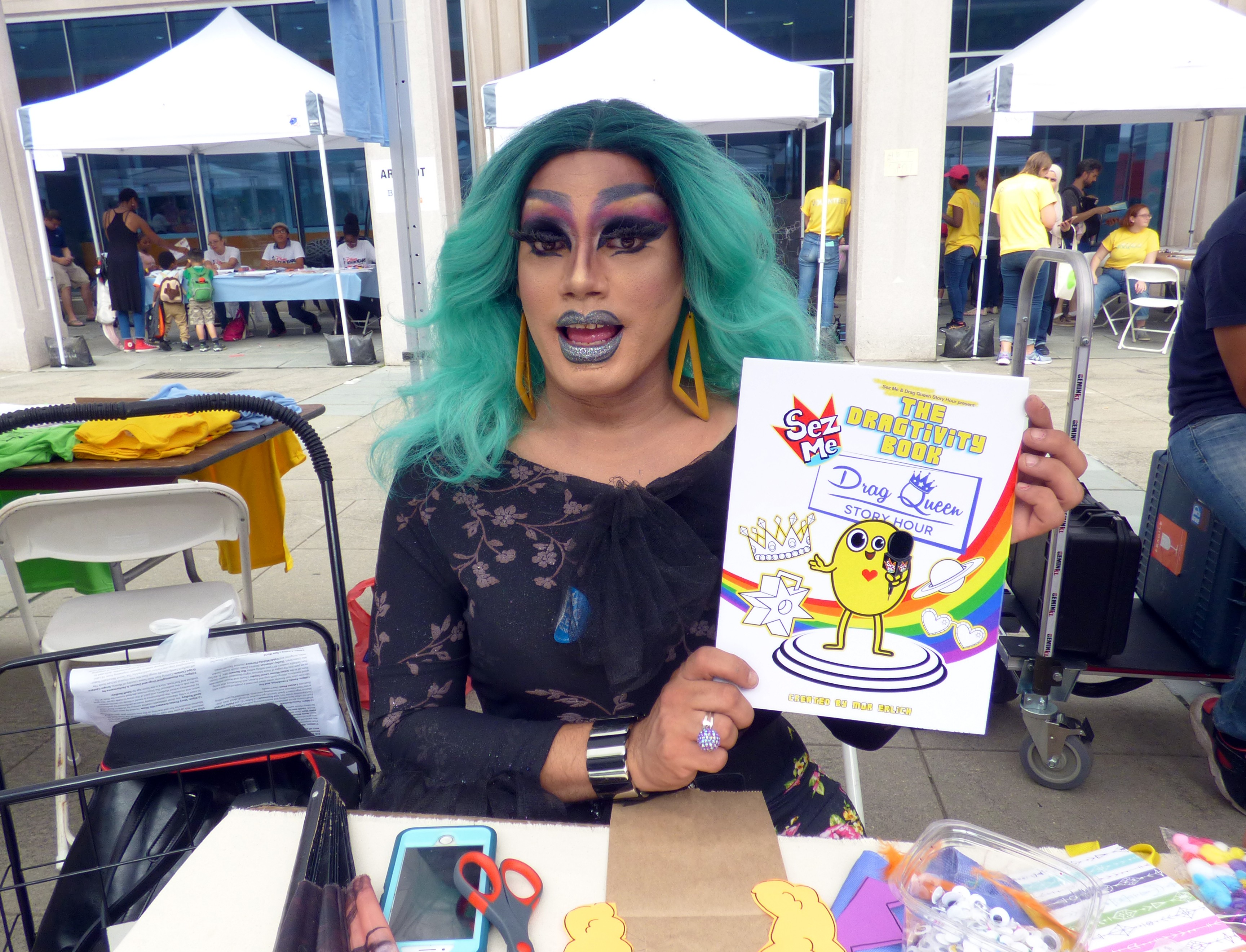 Angel Elektra, a drag queen who reads at Drag Queen Story Hours held at schools and libraries, shows the “Dragtivity Book” written by author Mor Erlich. The book includes activities for kids centered around drag, including finding their own drag names.