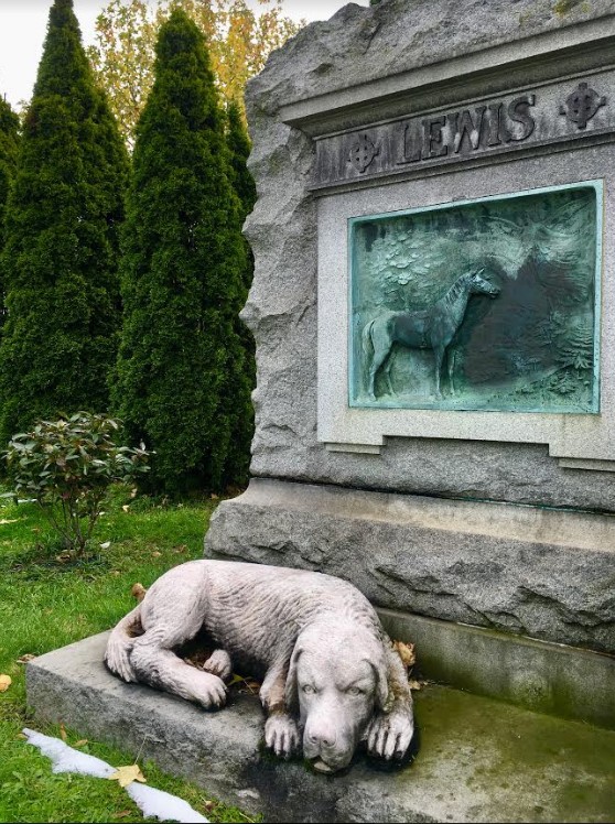 A sculptural dog watches over the grave of Burt G. Lewis. Eagle photo by Lore Croghan