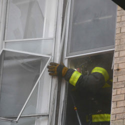Firefighter removes window to vent a burning apartment.