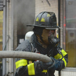 Firefighter in mask battles fire.