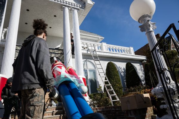 Nasti’s workers begin hoisting a toy soldier next to the columns of the Polizzotto house in Dyker Heights so Nasti can tie it off.