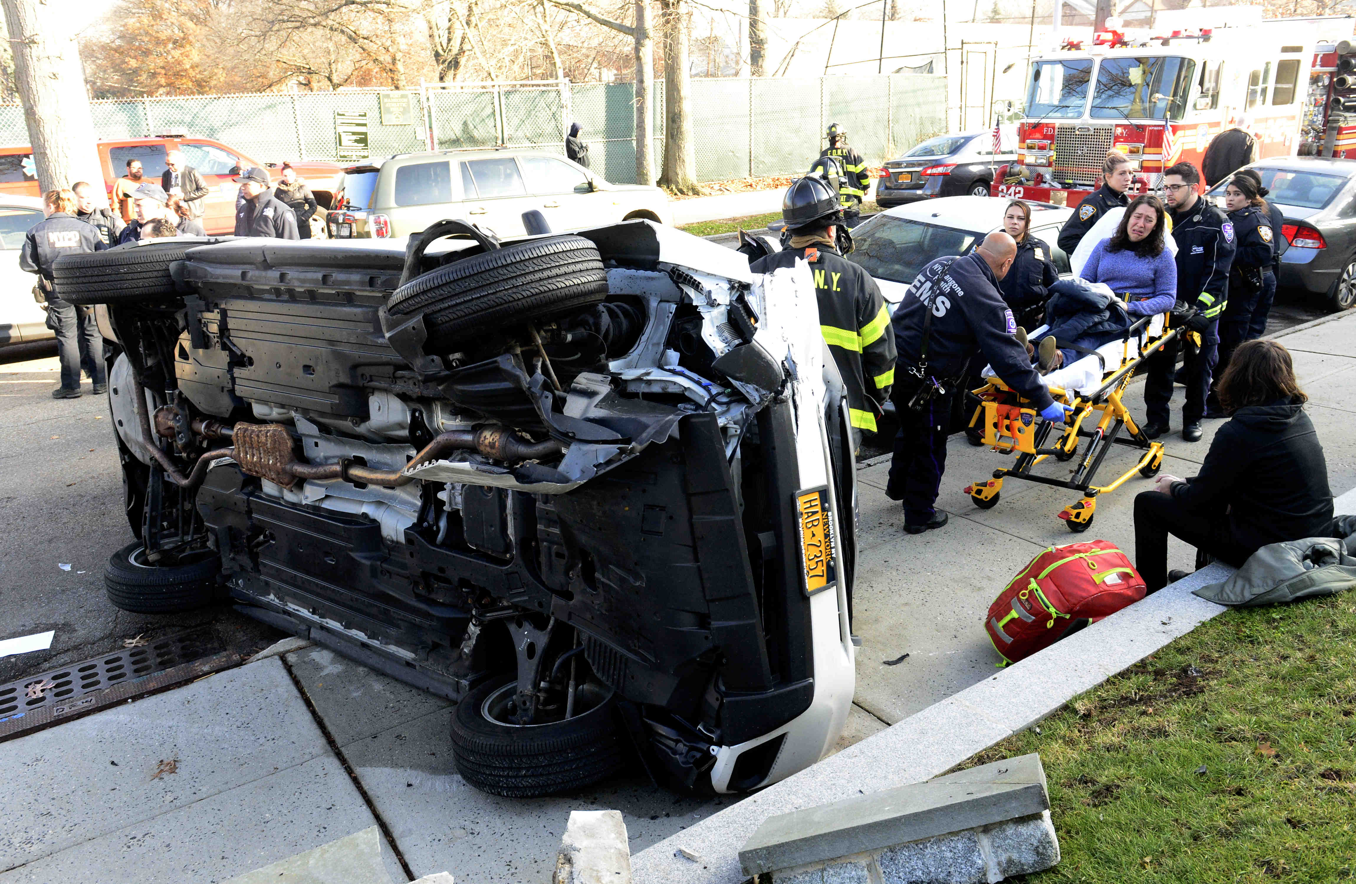 Police and firefighters help the injured victims of the crash on 85th Street next to Fort Hamilton High School Saturday. Eagle photos by Todd Maisel