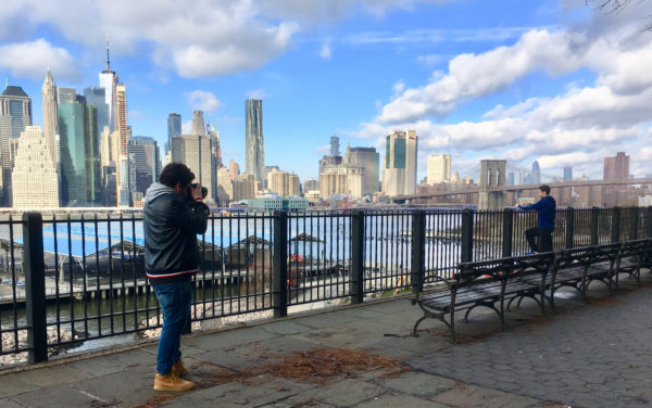 A Promenade visitor poses for pictures with the Brooklyn Bridge in the background. 