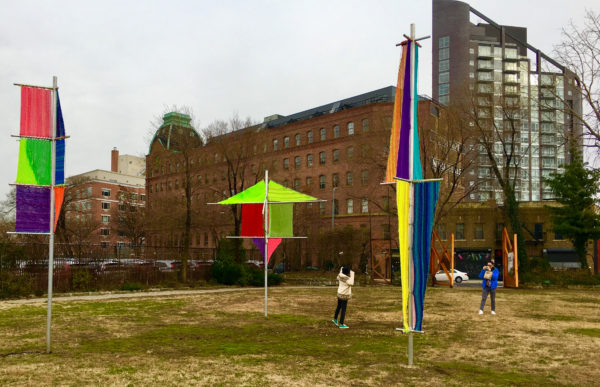 A Socrates Sculpture Park visitor poses for a picture beside Jesse Harrod's work “Flagging 1, 2, 3.”