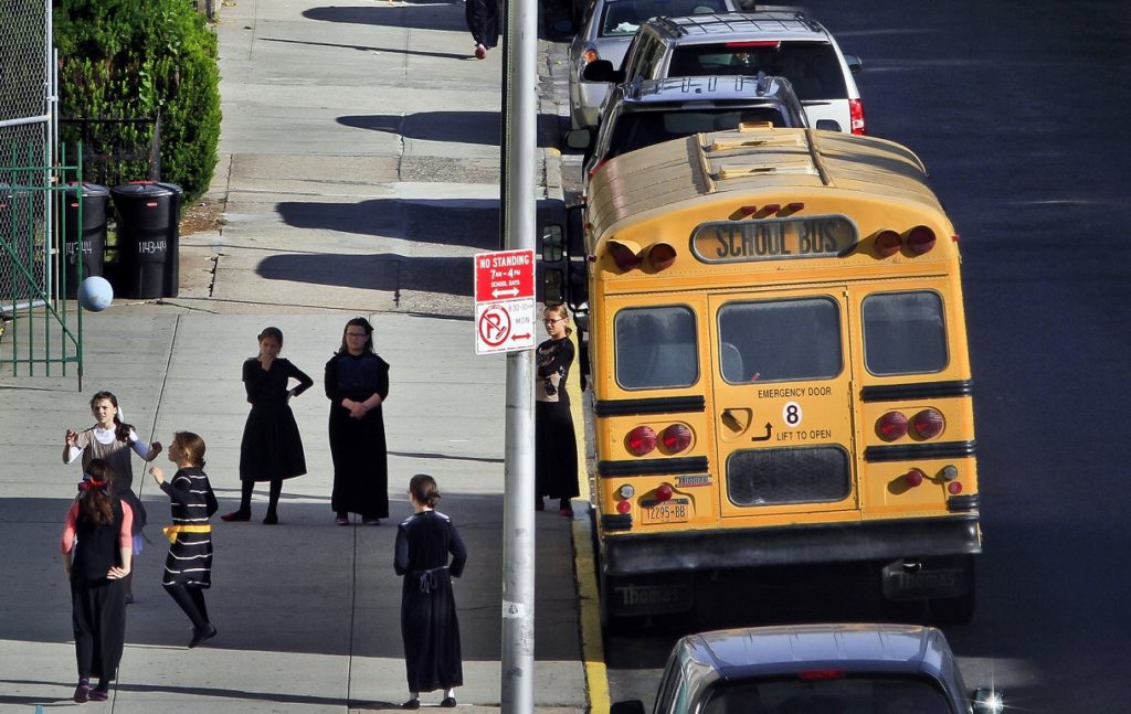 Measles is continuing to spread among ultra-Orthodox families in Brooklyn. Shown: Children gather on a sidewalk near school buses in Borough Park, one of the neighborhoods where the disease has been found. AP file photo by Bebeto Matthews