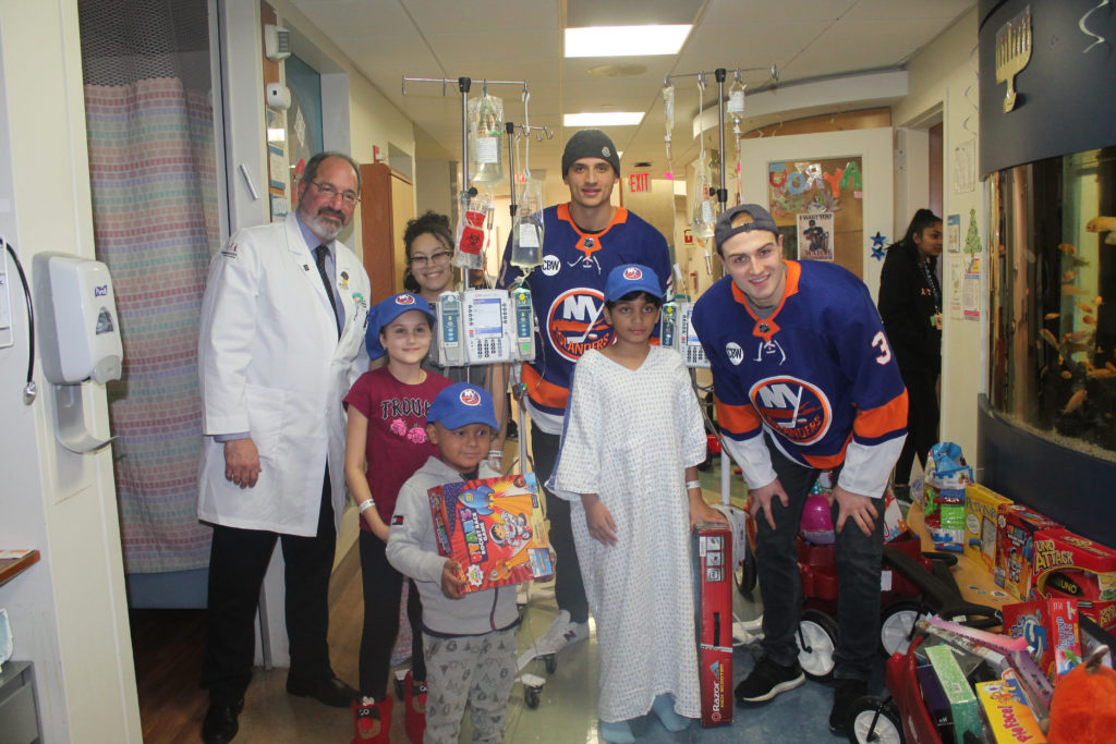 Islanders players Luca Sbisa and Adam Pelech with Dr. Jeffrey Avner and patients. Eagle photo by Jaime DeJesus