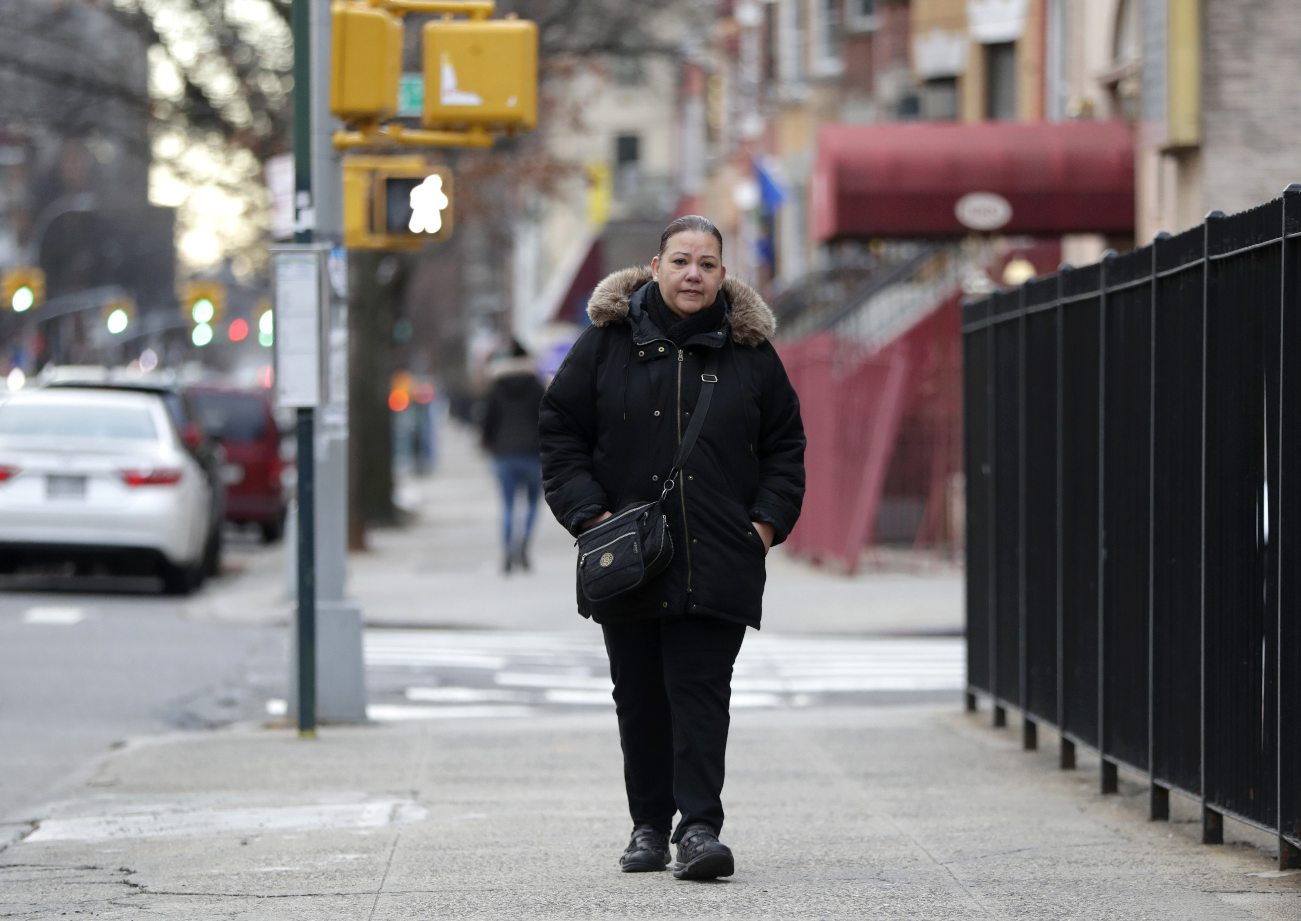 In a photo taken Sunday, Dec. 23, 2018, Flavia Cabral walks to her mother's home in the Bronx section of New York. Cabral, who works two jobs, will be among many people benefiting from the minimum wage raise which will hit $15 on Dec. 31st. (AP Photo/Julio Cortez)