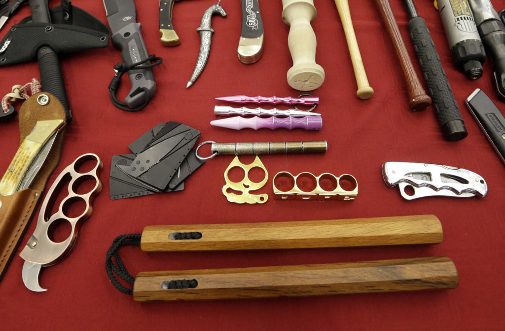 FILE - This April 6, 2017 file photo, of objects confiscated from passengers' carry-on luggage, including nunchucks, center, front, are displayed at Seattle-Tacoma International Airport, in SeaTac, Wash. A federal court says New York's ban on nunchucks, the martial arts weapon made famous by Bruce Lee but prohibited in the state for decades, is unconstitutional under the Second Amendment. (AP Photo/Elaine Thompson, File)
