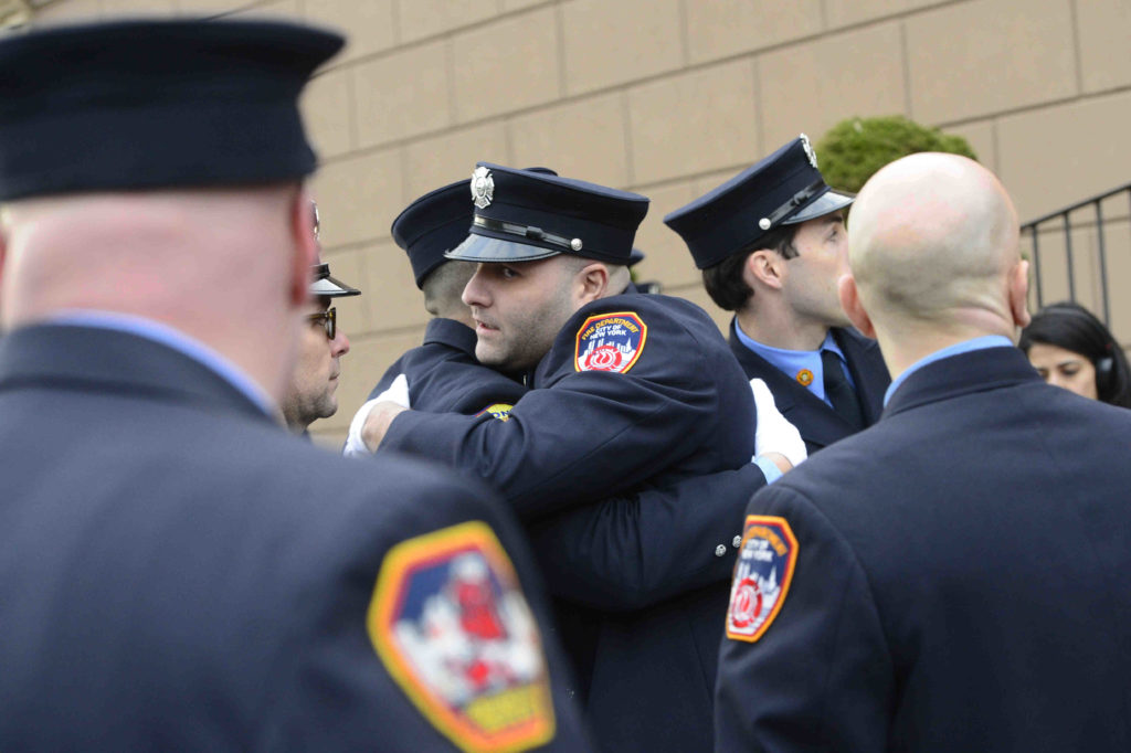 Firefighters embrace outside the wake for Faizal Coto. Eagle photo by Todd Maisel