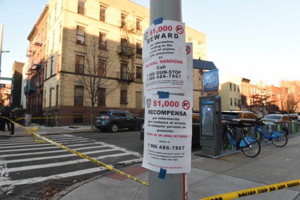 Posters at scene of shooting call for rewards to help get illegal handguns off the street on Pulaski Street and Marcus Garvey Blvd.