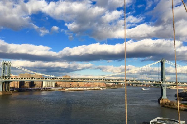 Puffy clouds float over the Manhattan Bridge, which is seen here from the Brooklyn Bridge's walkway.