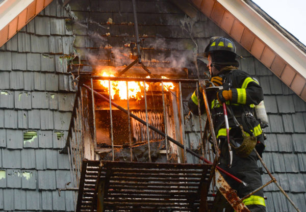 Firefighters attempt to gain entry to an attic window filled with fire in Midwood.