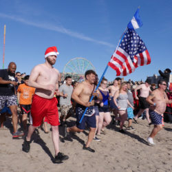 Roberto Velazquez proudly carries the American flag while attending the annual New Year’s Day Polar Bear Plunge at Coney Island.