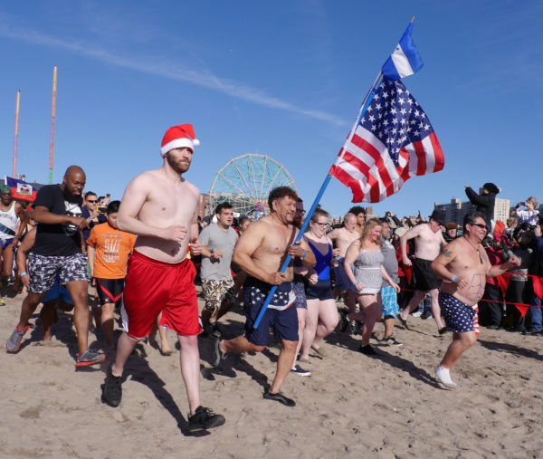 Roberto Velazquez proudly carries the American flag while attending the annual New Yearâs Day Polar Bear Plunge at Coney Island.