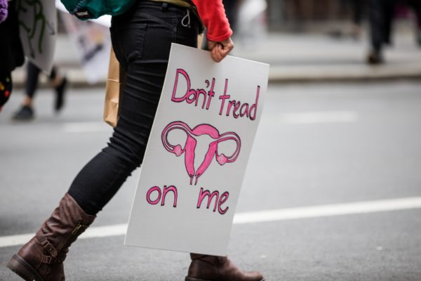 A woman carries her sign at the end of the uptown march.
