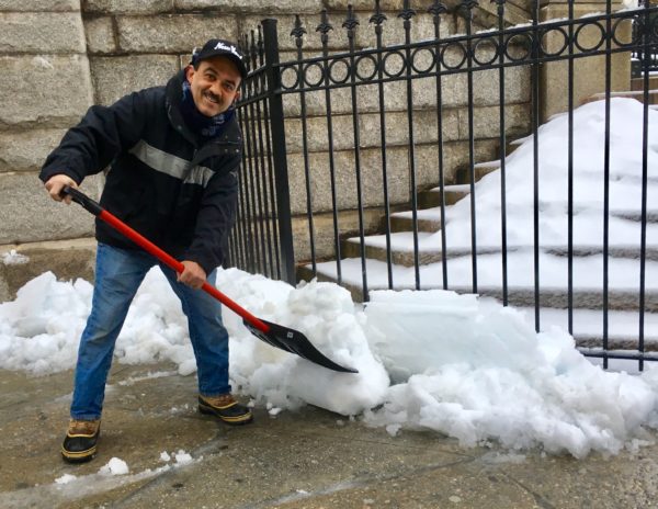 Isidro Frias smiles while he shovels the sidewalks outside Our Lady of Perpetual Help. 