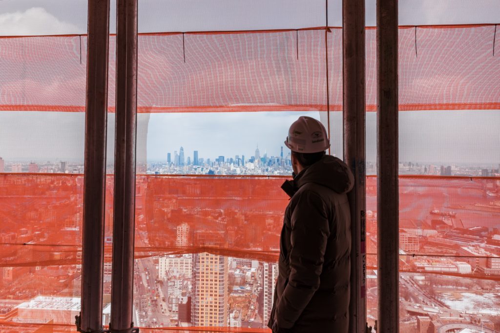 Ari Goldstein, vice president for development at Extell, looks through construction netting to see a view of Midtown and the Empire State Building. Eagle photo by Paul Frangipane.