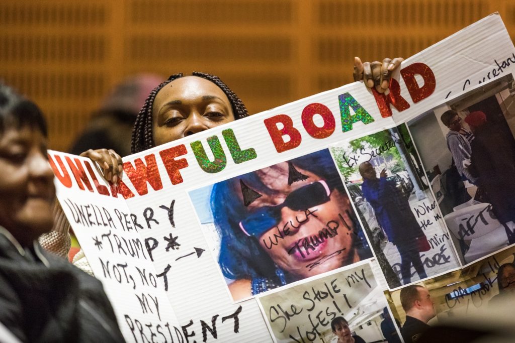 Harry Silver Co Inc. shareholder Marcella Coma holds a sign protesting Unella Perry at the Community Board 9 general meeting on March 26. Eagle photo by Paul Frangipane