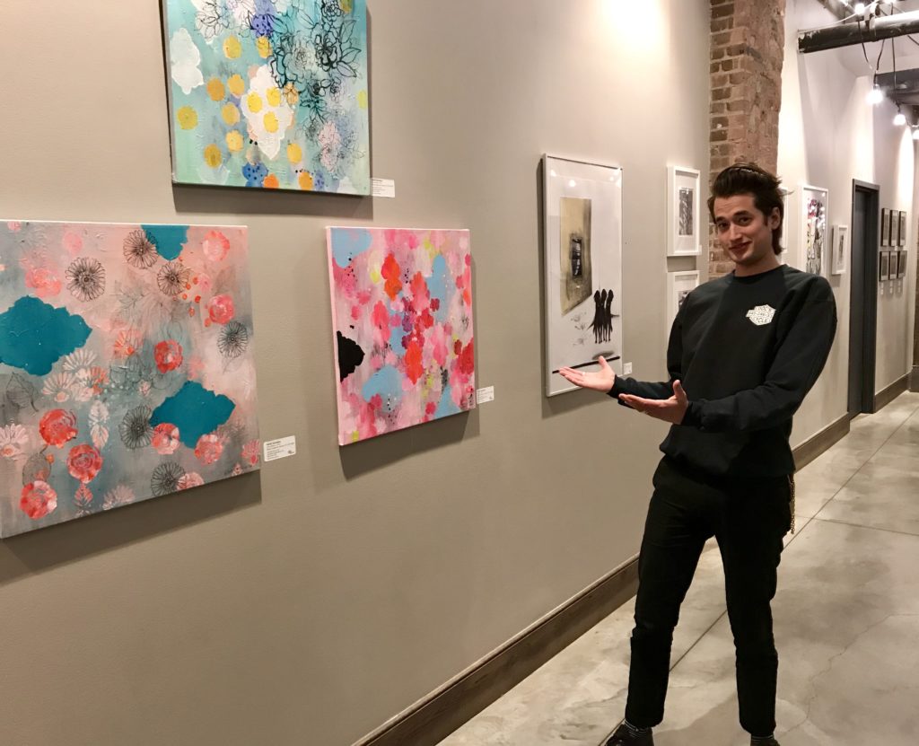 Chris Adams, who runs marketing and events for the Empire Stores building, with artwork on display at Gallery 55. This month’s show is by artists affiliated with Park Slope Windsor Terrace, a Brooklyn-based artist collective. Eagle photo by Mary Frost