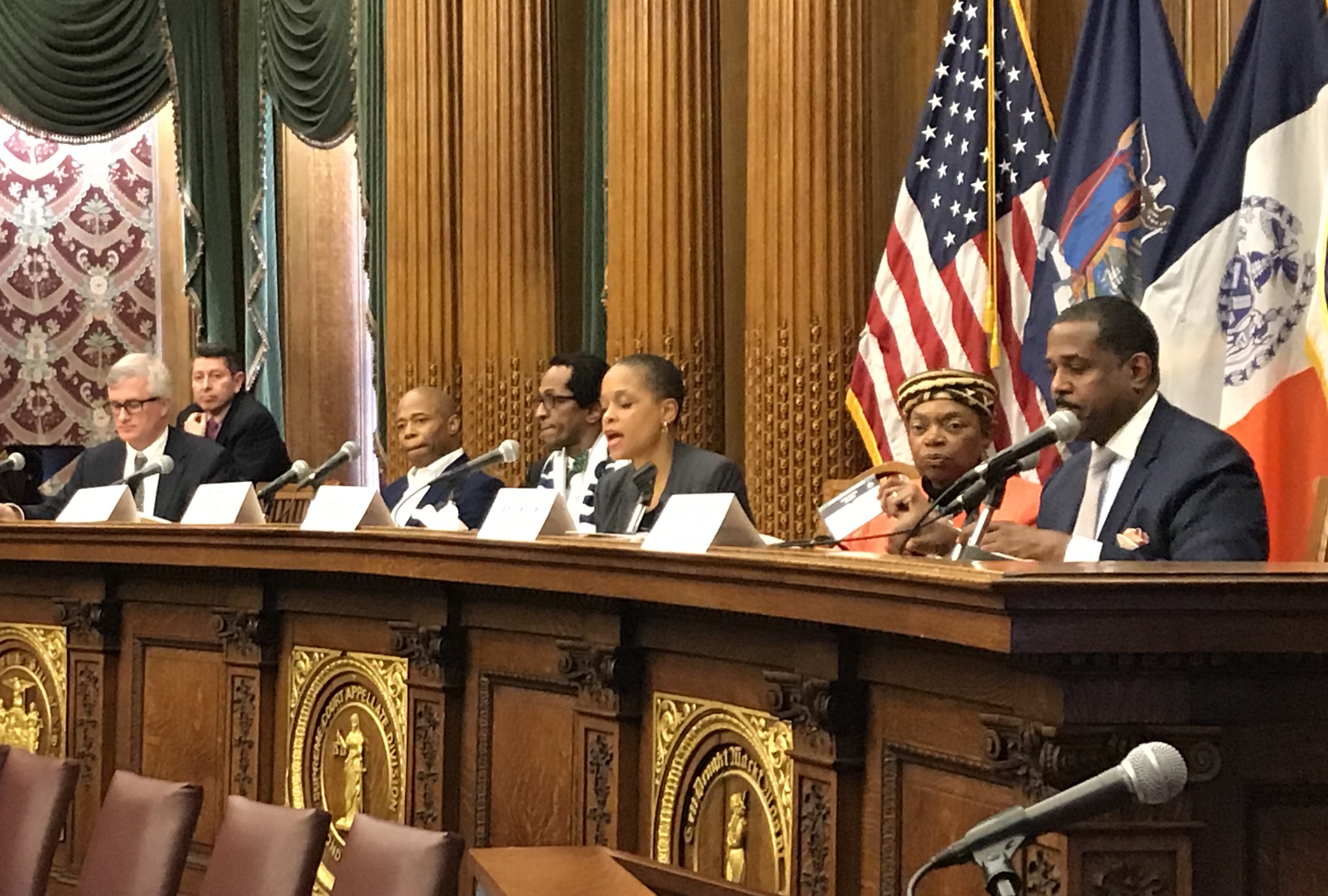 Brooklyn Borough President Eric Adams (third from left), Assemblymember Tremaine Wright (center, speaking) and State Senator Velmanette Montgomery (sixth from left) sponsored a packed hearing on the housing theft crisis in Brooklyn. Eagle photo by Mary Frost.
