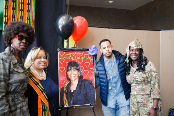 Sometimes Leah Richardson (pictured right) gets enough time to pause and present someone with an award during the fashion show. In 2018, she and Justices Hon. Sylvia Ash (left) and Hon. Deborah Dowling (second from left) honored Izetta Johnson (pictured on poster) by inviting her son Ashley Johnson (second from right) to be recognized on behalf of his mother. Eagle file photo by Paul Frangipane