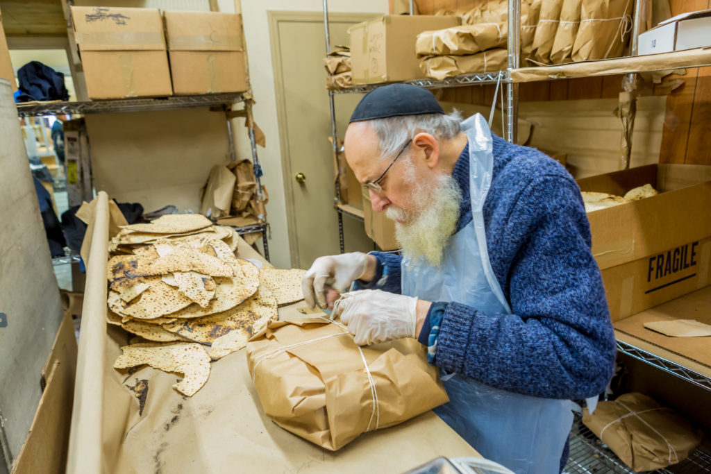 A worker at the Lubavitch Matzah Bakery in Crown Heights wraps a bundle of shmurah matzos. Photo courtesy of Rabbi Chaim Landa, Chabad Lubavitch