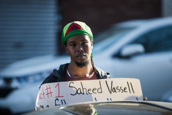 Community members at the vigil carried signs displaying the facts of Saheed Vassell's death. Eagle photo by Paul Frangipane