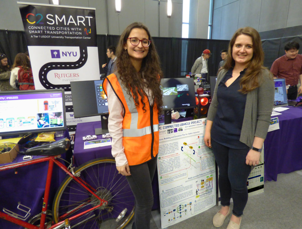 Grad student Suzana Duran Bernardes (left) and Alyssa Brewer, communications associate for C2SMART, display some of the research on ‘smart transportation’ the group is doing at NYU Tandon. The director of C2SMART, Kaan Ozbay, was just appointed to Mayor Bill de Blasio’s BQE panel. Eagle photo by Mary Frost