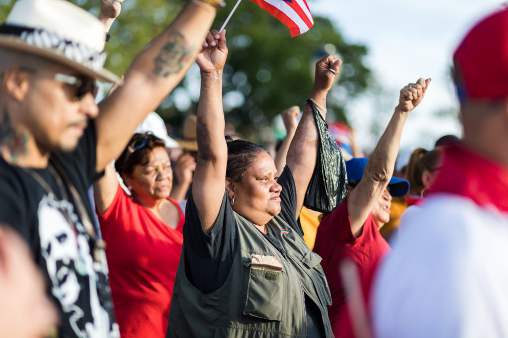 Crowd members raise their fists in unity as speakers touch on political and human rights issues affecting the Puerto Rican community. Eagle photo by Paul Frangipane