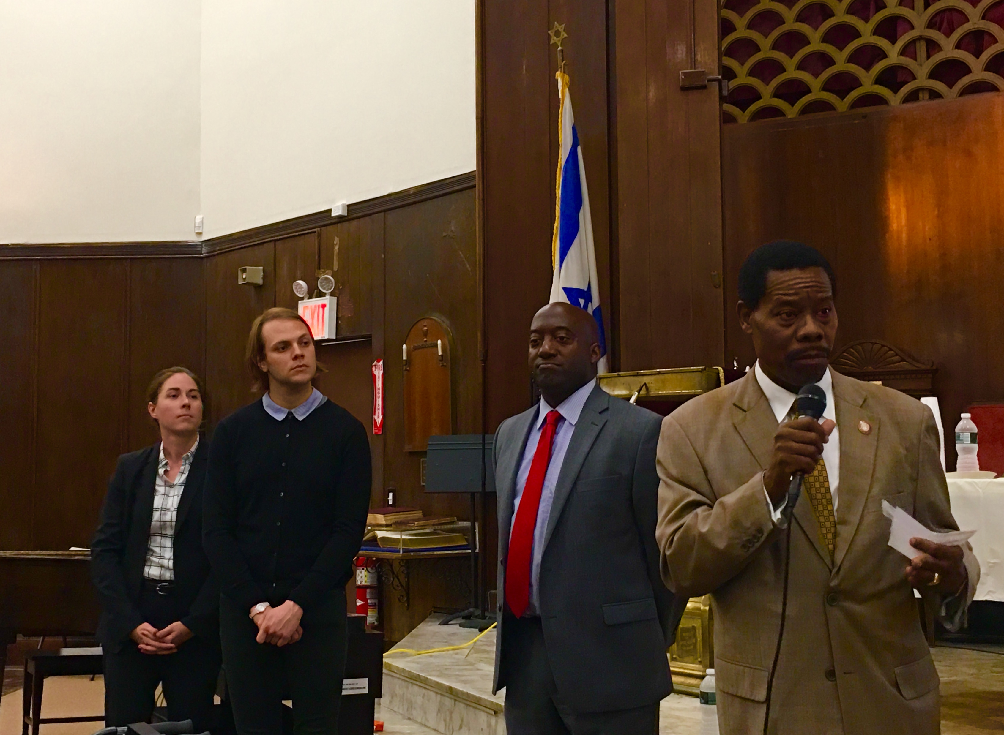 Councilmember Mathieu Eugene, at right, speaks at a public forum. DOT Brooklyn Borough Commissioner Keith Bray, second from right, and DOT’s Ryan Feller and Allison Bullock stand by. Eagle photo by Lore Croghan