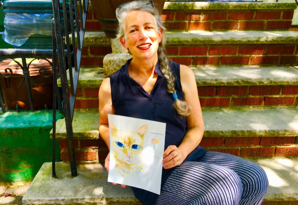 Emily Waters, seen here with a watercolor she painted of her cat, Bamboo, gives away an artwork every week. Eagle photo by Lore Croghan