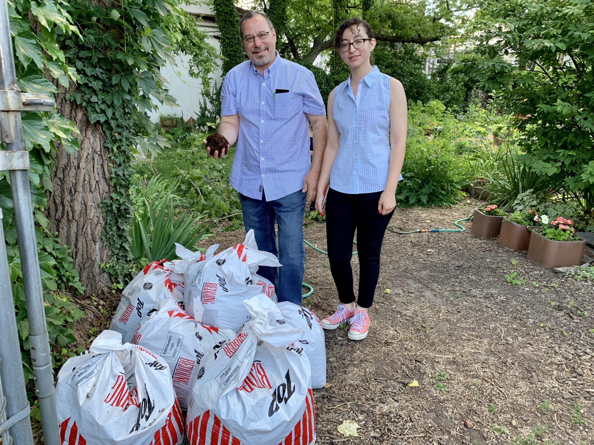 John Quadrozzi Jr., left, and his daughter Xiana rip open one of the first bags of composted manure delivered to Red Hook’s Backyard Community Garden on Sunday. Xiana is a partner with her dad in Prospect Park Stable. Eagle photo by Mary Frost