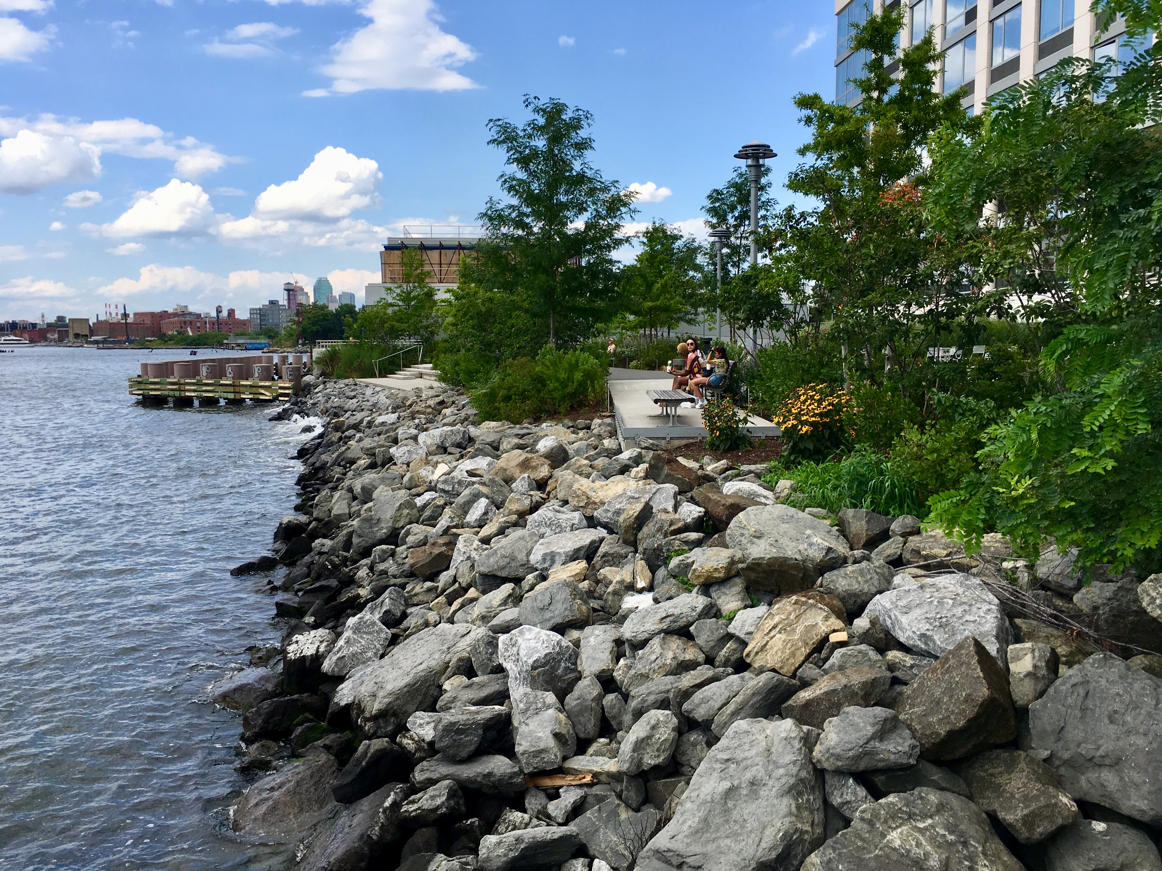 Boulders create a barrier between the lapping waters of the East River and the public space behind Level BK. Eagle photo by Lore Croghan