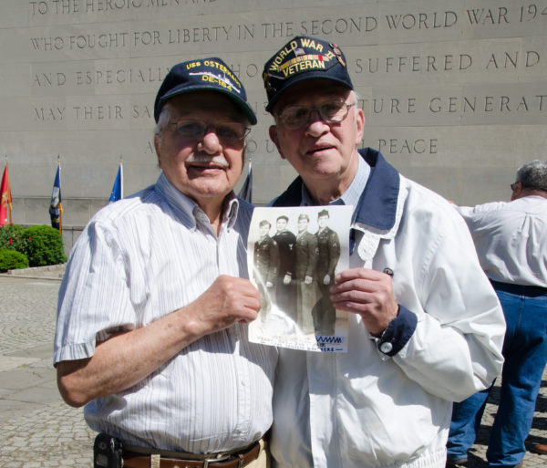 WWII veteran brothers Roy and Jack Vanasco at the Brooklyn War Memorial in 2015, holding a photo showing all four of the Vanasco brothers in uniform. Photo courtesy of Toba Potosky