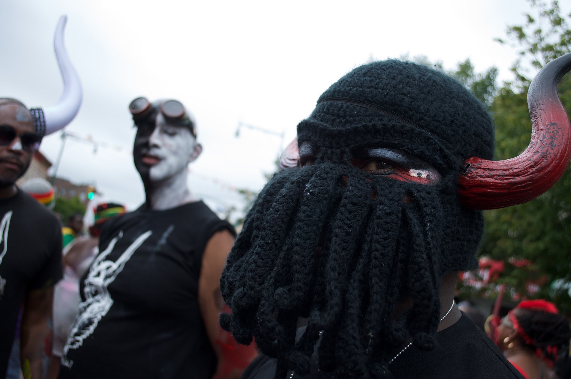 A reveler wearing a knit hat with demon horns poses for the camera.