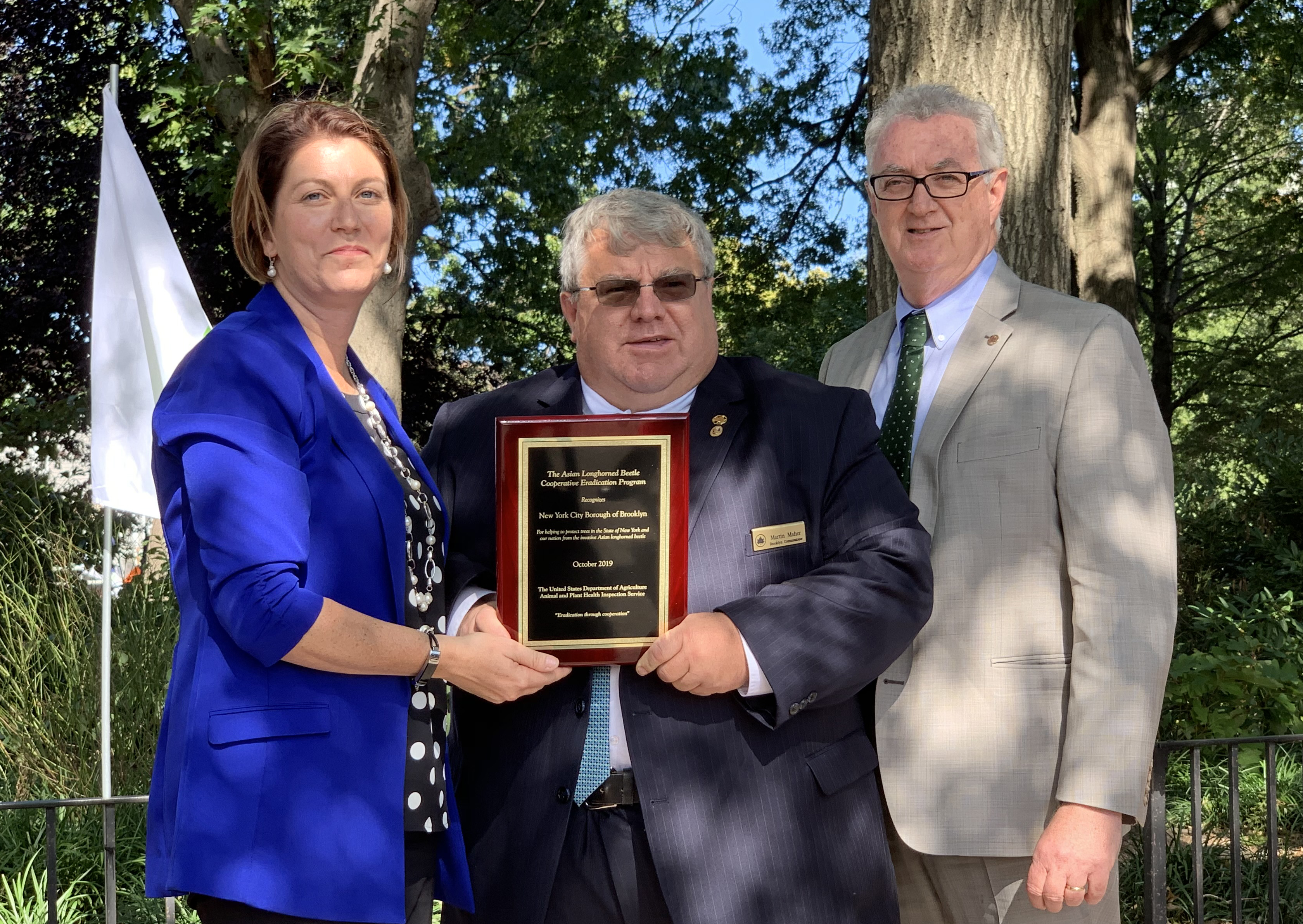 Brooklyn Parks Commissioner Marty Maher, center, accepts a plaque celebrating Brooklyn’s eradication of the invasive pest. With him stand USDA’s Samantha Simon and NYC Parks First Deputy Commissioner Liam Kavanagh. Eagle photo by Mary Frost
