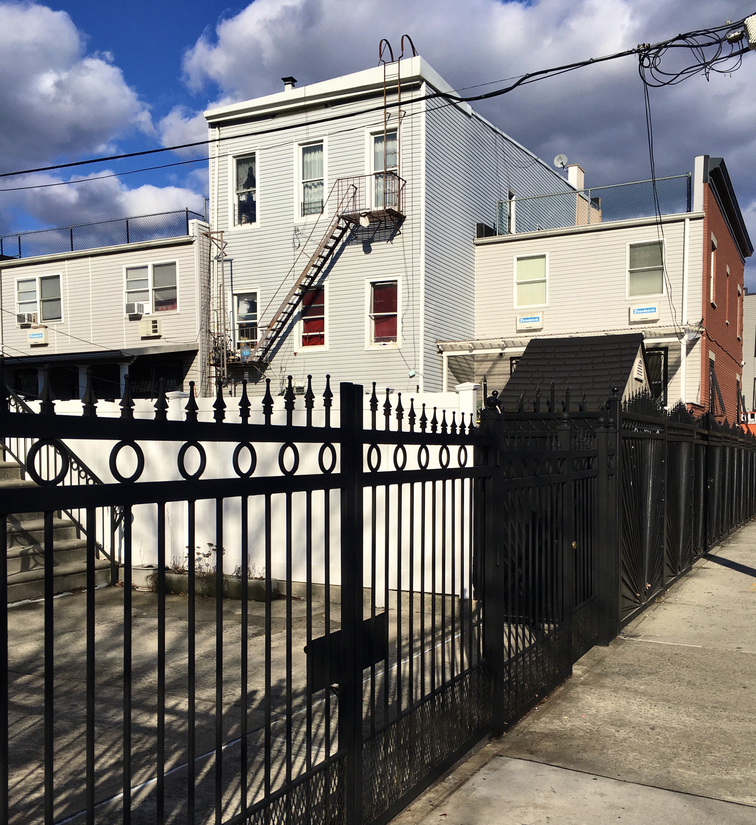 From the Gates Avenue sidewalk, you see the sunlit back facades of rowhouses on Central Avenue. Photo: Lore Croghan/Brooklyn Eagle