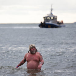 A man erupts from below the surface of the waves to look around while an NYPD patrol boat scopes the scene.