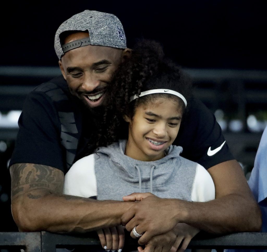 In this July 26, 2018 file photo former Los Angeles Laker Kobe Bryant and his daughter Gianna watch during the U.S. national championships swimming meet in Irvine, Calif. Bryant, the 18-time NBA All-Star who won five championships and became one of the greatest basketball players of his generation during a 20-year career with the Los Angeles Lakers, died in a helicopter crash Sunday, Jan. 26, 2020. Gianna also died in the crash. She was 13. AP Photo/Chris Carlson