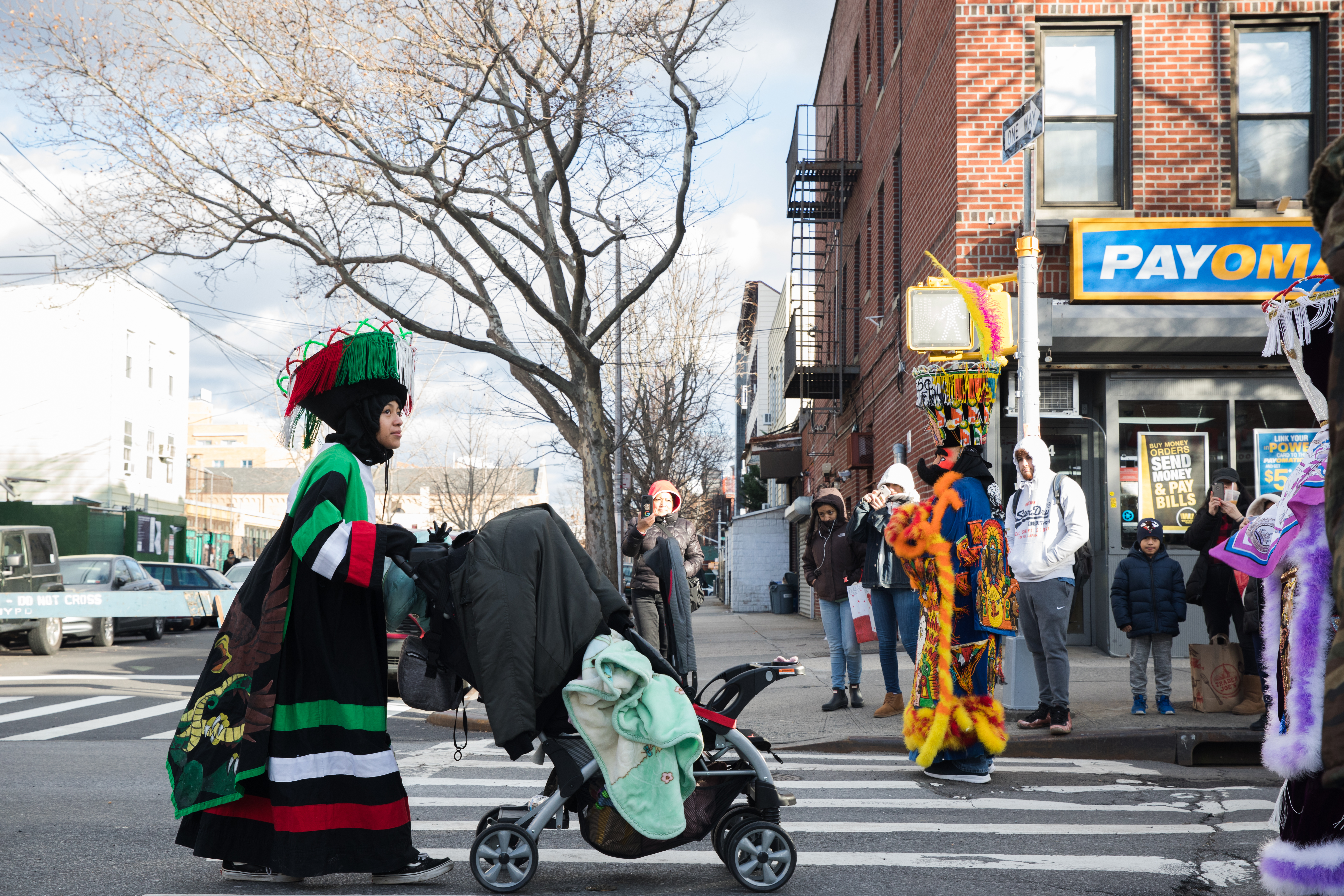 A woman in traditional Mexican dance attire pushes a stroller along the parade route.