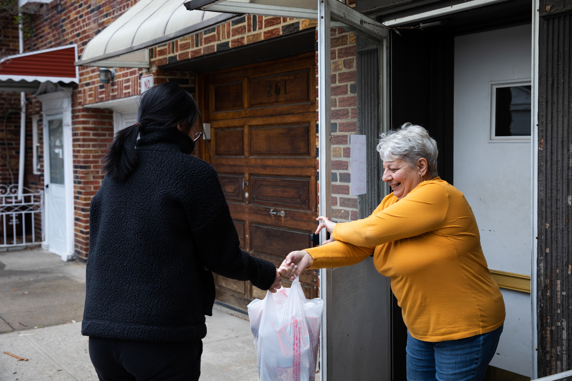 Theresa Monforte-Caraballo of Grandma’s Love hands a care package to a volunteer with Bay Ridge Cares. The volunteer will take the food to a family in Gravesend who can’t leave their home during the coronavirus pandemic. Photo: Paul Frangipane/Brooklyn Eagle