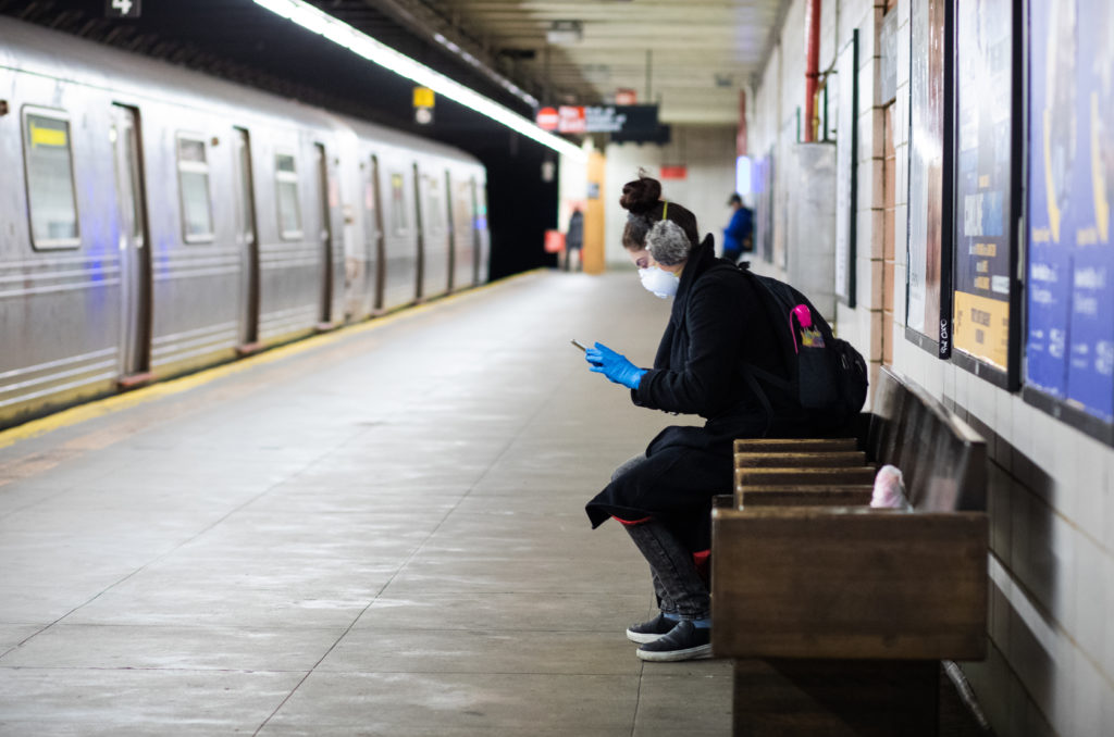 A woman wears a mask and gloves waiting for a Manhattan bound R Train at the 77th Street Station in Brooklyn on March 12, 2020. Photo: Paul Frangipane/Brooklyn Eagle