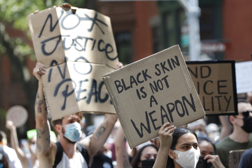 Protesters held signs as they marched through the streets of Bed-Stuy on Sunday. Photo: Kathy Willens/AP