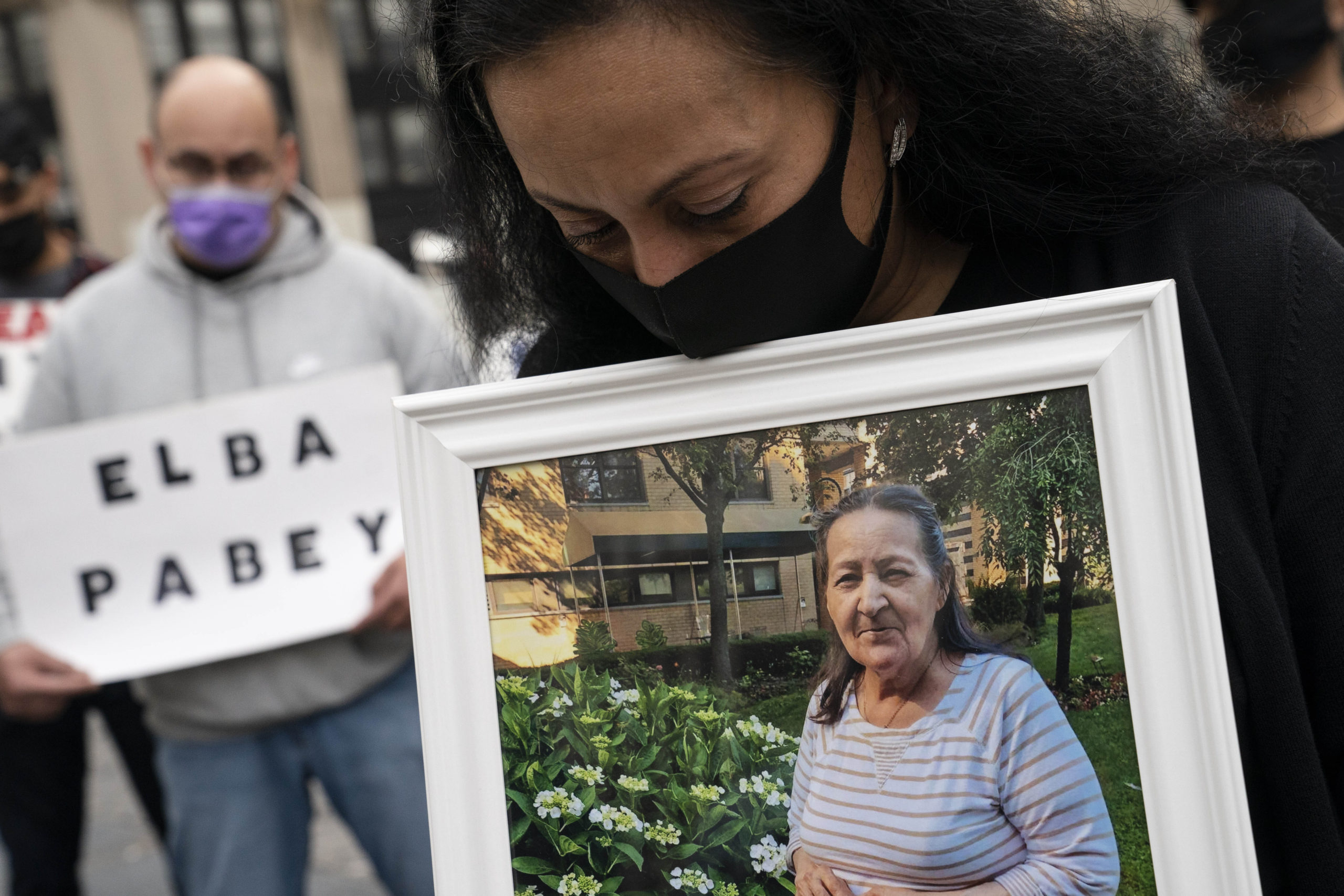 In this March 25, 2021 file photo, Haydee Pabey holds a picture of the deceased Elba Pabey as demonstrators gather for a rally decrying New York Gov. Andrew Cuomo's handling of nursing homes during the previous years outbreak of COVID-19, in New York. AP Photo/John Minchillo