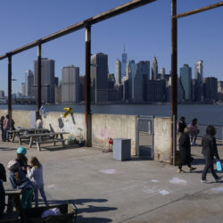 People enjoy the sunny weather and a view of the Manhattan skyline from the Brooklyn waterfront, March 21, 2021, in New York. AP Photo/Seth Wenig, File