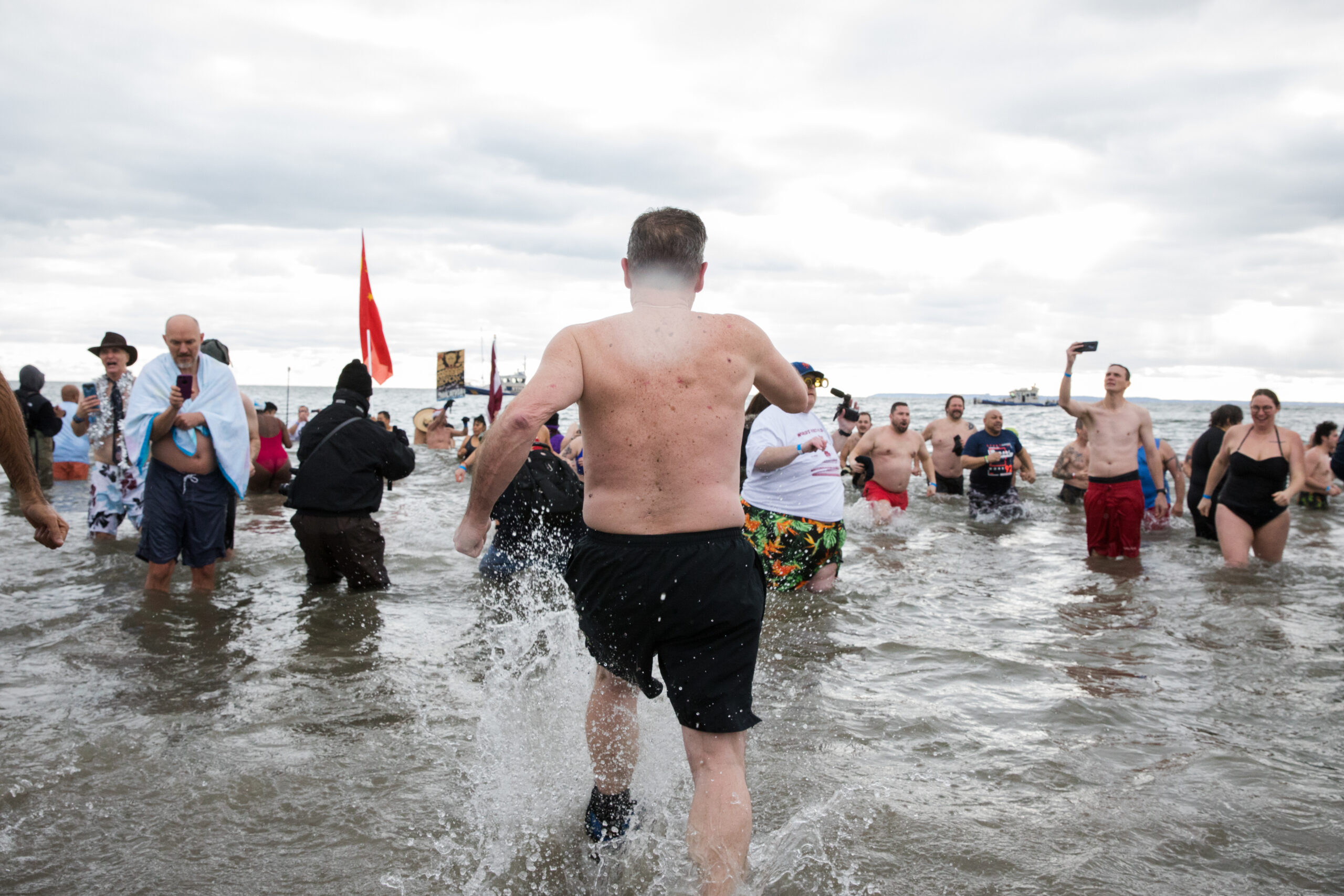 A man lifts his knees as he marches into the ocean to meet his fellow plunge participants.