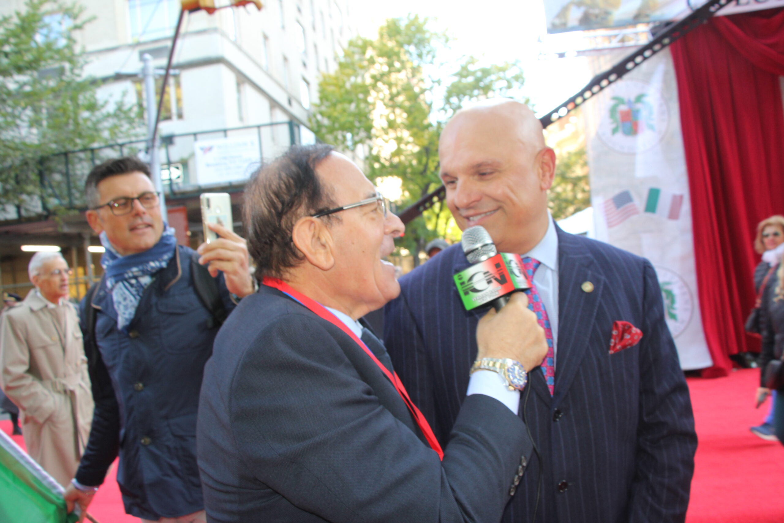 Arthur Aidala, engaged in an interview, brings the event into homes across New York as he discusses the importance of Italian-American heritage.