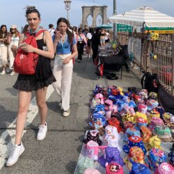 Pedestrians walk by vendors on Brooklyn Bridge