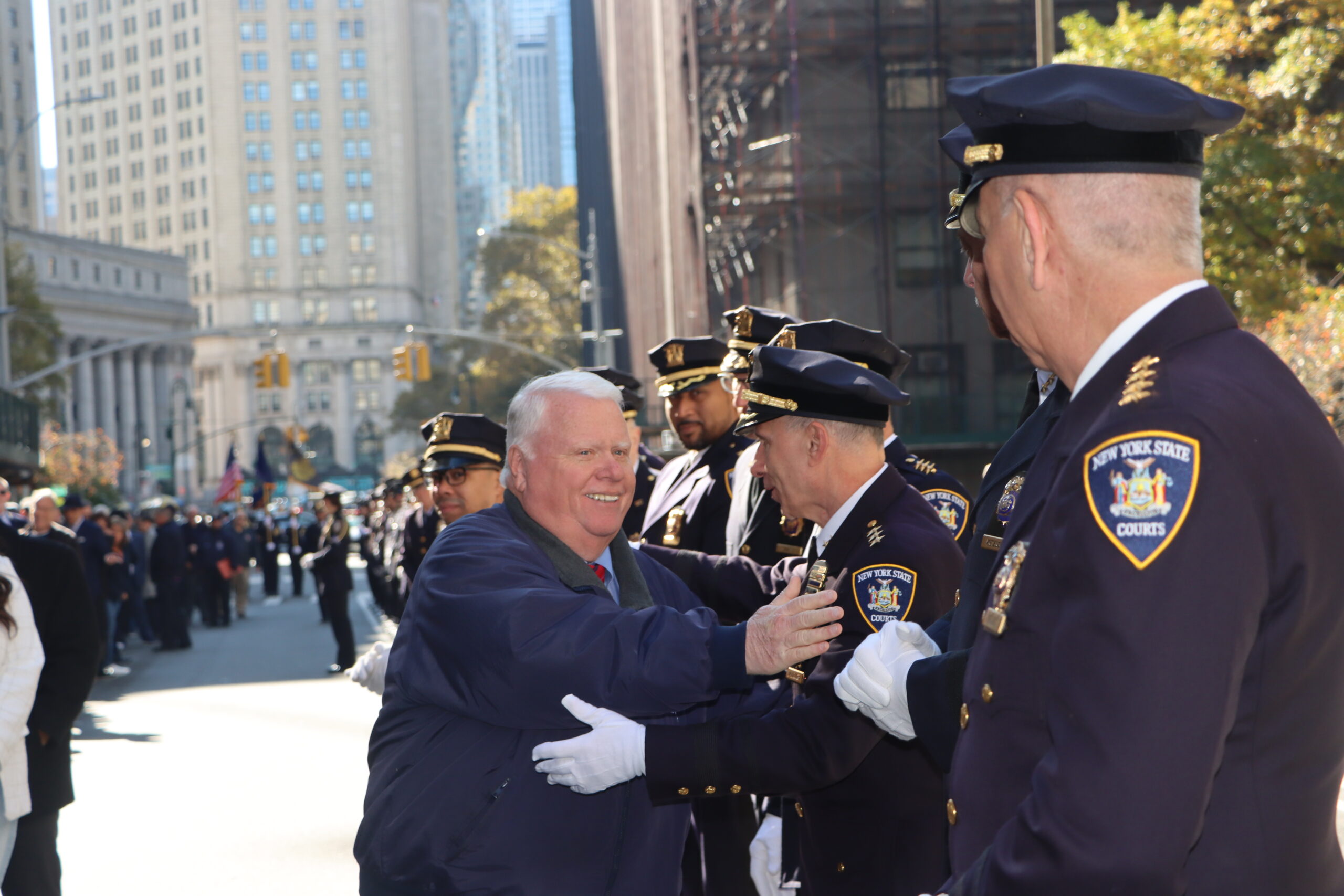 Dennis Quirk receives a warm handshake as he strolls down the closed Centre Street, flanked by court officers from the union he led for five decades.Photos: Mario Belluomo/Brooklyn Eagle